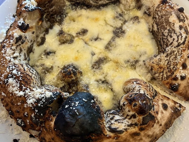 Close up of a leopard-spotted Neapolitan crust and melted cheese.
